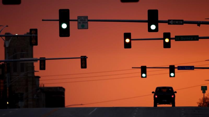 A motorist waits at a stoplight on an empty street as the sun sets during a coronavirus lockdown on April 28 2020 in downtown Topeka city US